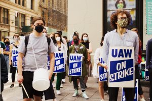 students in masks, social distancing, wearing signs saying UAW on strike